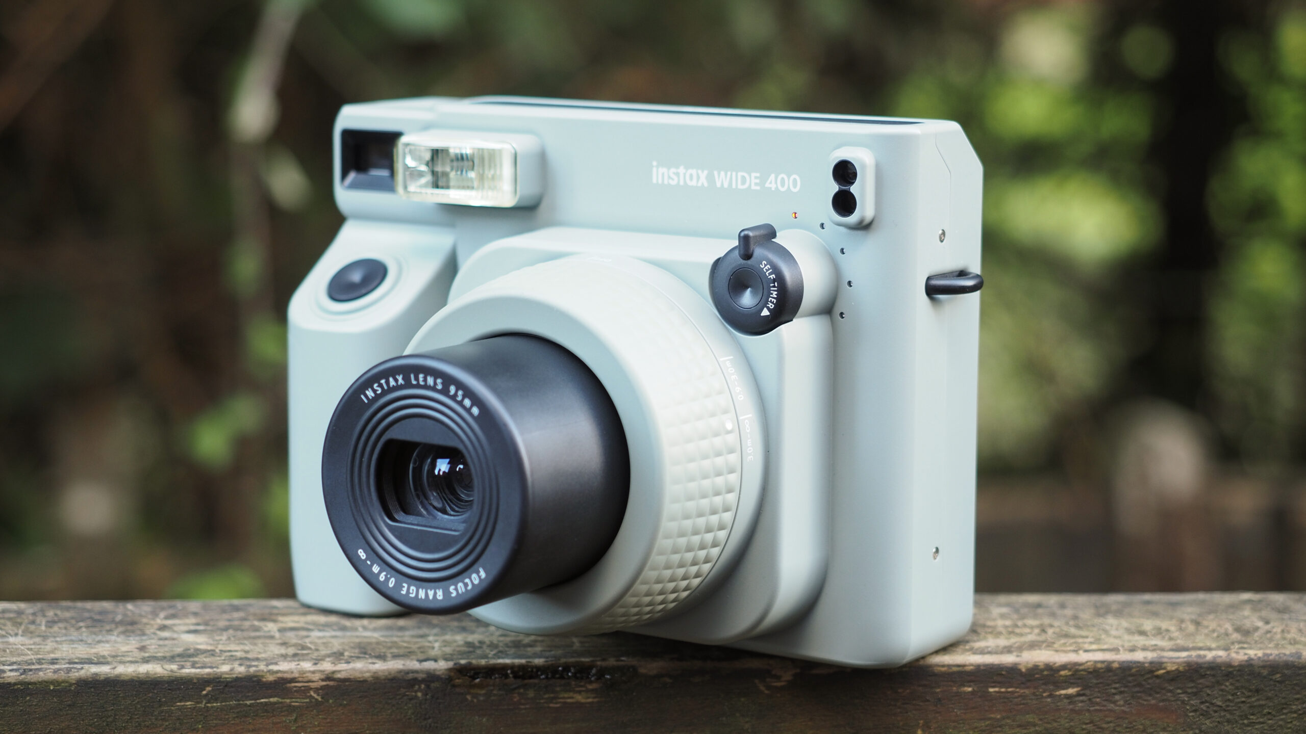fujifilm-thang-lon-red-dot-award-x-m5-x100-vi_03-scaled-1 Máy ảnh Instax Wide 400 đặt trên bề mặt gỗ giữa rừng cây